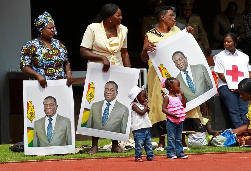 Women hold portraits of the new president. Tsvangirayi Mukwazhi / AP Photo