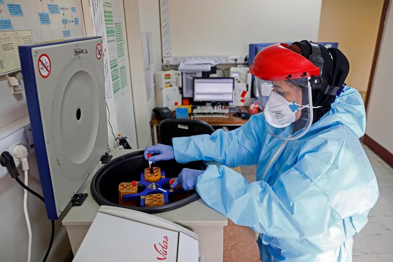 In this Sunday, March 1, 2020 photo, a paramedic works with a centrifuge to test blood samples taken from patients suspected of being infected with the new coronavirus, at a hospital in Tehran, Iran. Mizan News Agency via AP