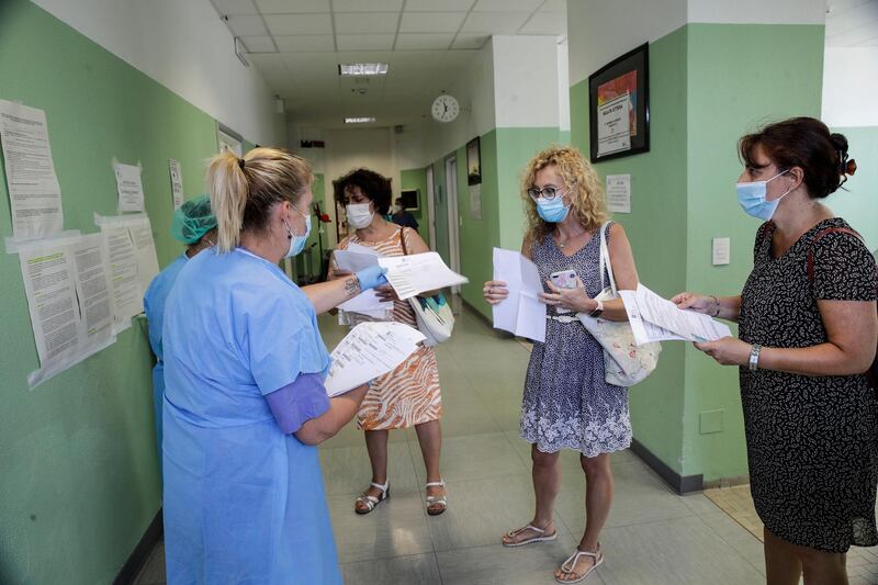 A medical worker distributes papers to teachers and school staff waiting for a blood Covid-19 test at the San Carlo Hospital in Milan, Italy. AP Photo