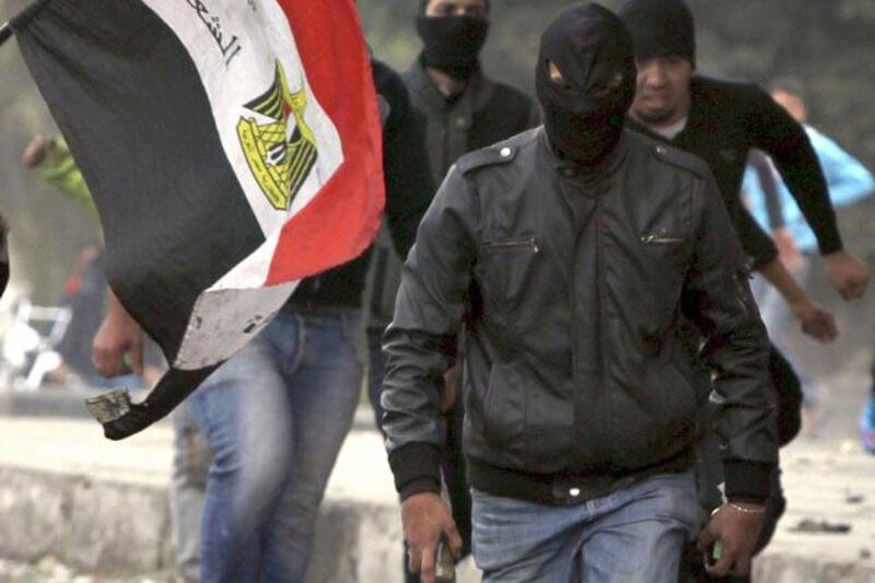 Members of the Black Bloc who oppose Egyptian President Mohamed Mursi run with Molotov cocktails during clashes with riot police, along Qasr Al Nil bridge, which leads to Tahrir Square in Cairo January 28, 2013. Monday was the fifth day of violence in Egypt that has killed 50 people and prompted the Islamist president to declare a state of emergency in an attempt to end a wave of unrest sweeping the Arab world's biggest nation. REUTERS/Amr Abdallah Dalsh (EGYPT - Tags: POLITICS CIVIL UNREST)