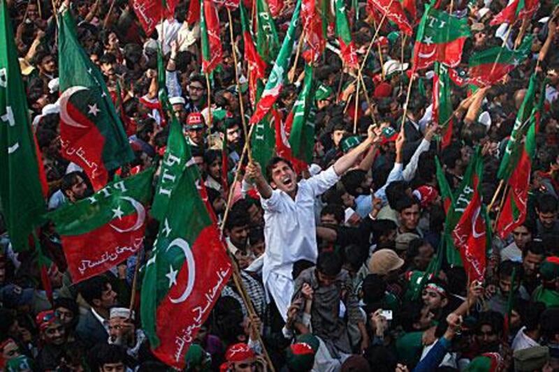 Supporters of the Pakistan Tehreek-e-Insaf political party wave the party’s flag during a rally in Karachi on Sunday. The party, led by the cricketer-turned-politician, Imran Khan, attracted about 100,000 people to the demonstration.