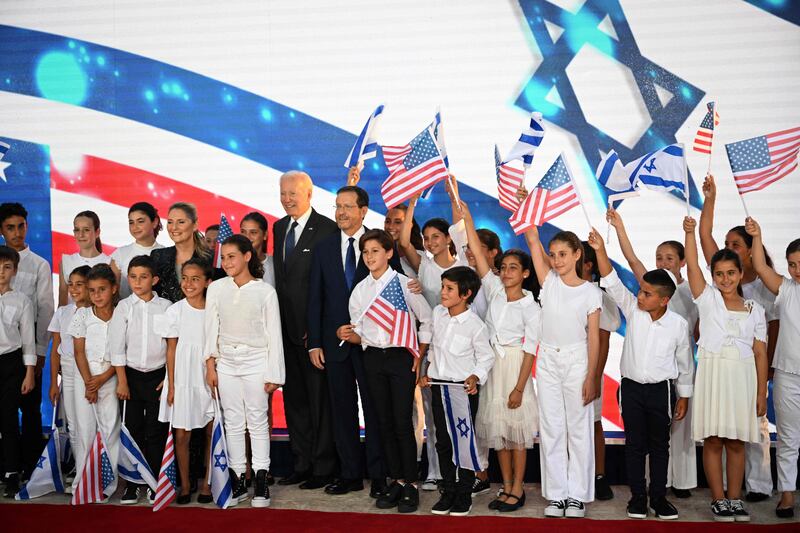 US President Joe Biden, centre left, and President Isaac Herzog with children after Mr Biden's arrival at the presidential residence in Jerusalem. AFP