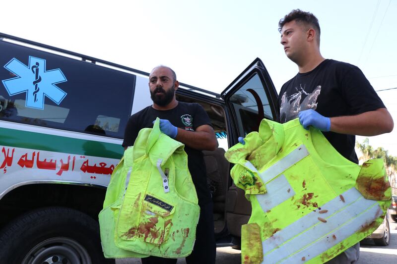 Lebanese parademics show the blood-stained high-vis jackets of four of their colleagues wounded after their ambulances were hit in a strike on the Lebanese town of Tayr Harfa. AFP
