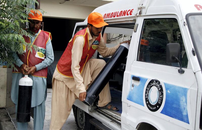 Aziz Ullah, 60, and 21-year-old Muhammad Usman, two aid workers of Alamgir Welfare Trust are loading cylinders in a vehicle in Islamabad for their delivery to COVID-19 patients. Imran Mukhtar/ The National 