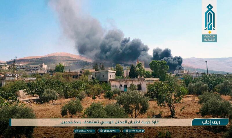 This photo released Tuesday, Sept 4, 2018 by the al-Qaida-affiliated Ibaa News Agency, shows smoke rising over buildings that were hit by airstrikes, in Mahambal village, in the northern province of Idlib, Syria. Arabic reads, "Air raid by the Russian occupation plane on Mahambal village." (Ibaa News Agency, via AP)