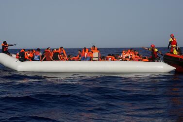 A lifeguard gives a thumbs-up to a migrant at the other end of a rubber boat in the middle of a rescue operation off the Libyan coast. AP Photo