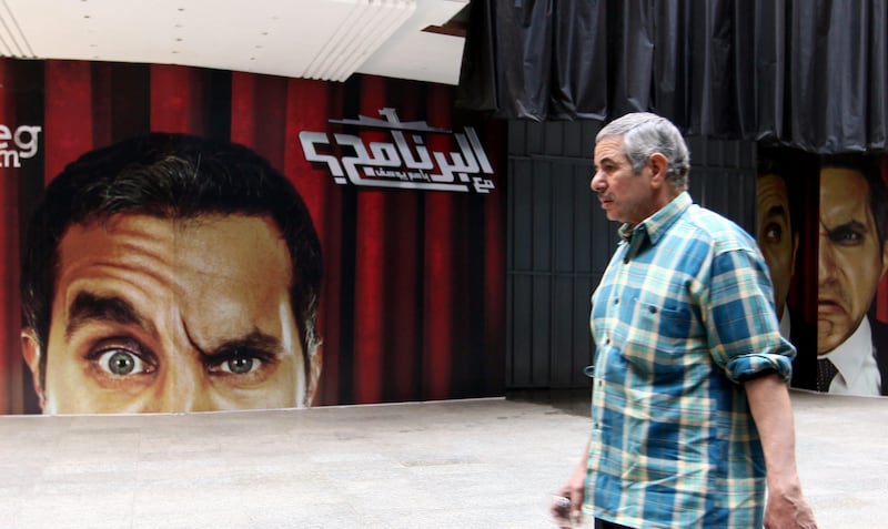 epa03522304 An Egyptian man walks in front of banners depicting Egyptian satirical TV show host Bassem Youssef in front of a theater in Cairo, Egypt, 02 January 2013. Egyptian prosecutors on 01 January began investigating Youssef for allegedly defaming President Mohamed Morsi on his program. Youssef has been satirizing speeches by Islamists in his recent episodes, broadcast on a private Egyptian Satellite channel. Youssef is known as "Egypt's Jon Stewart" - a reference to the US political satirist who hosts Comedy Central's Daily Show.  EPA/KHALED ELFIQI *** Local Caption ***  03522304.jpg