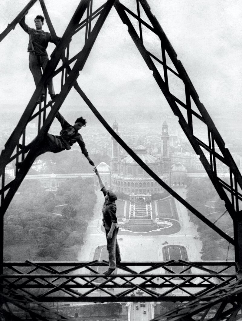 Picture released in the 30s in Paris shows "acrobatic" workers on the Eiffel Tower in front of the Trocadero Palace. (Photo by STRINGER / AFP)