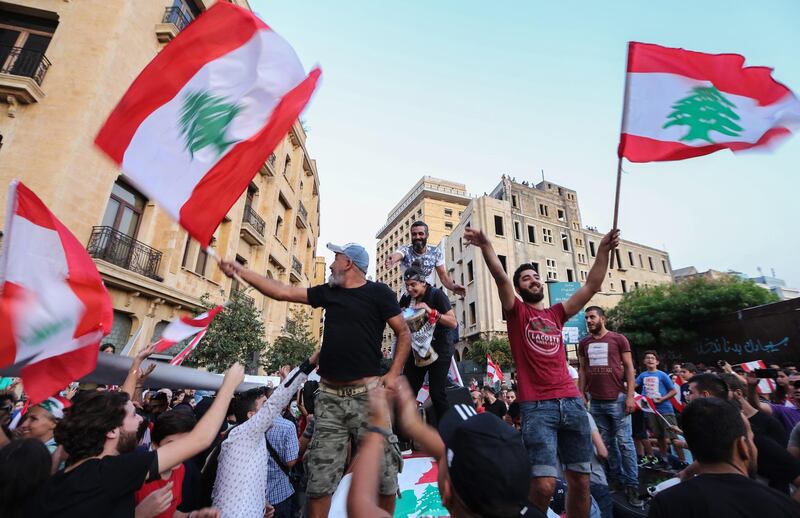 epa07941572 Protesters carry placards, wave Lebanese flags and shout anti-government slogans during a protest in front the Government palace in downtown Beirut, Lebanon, 22 October 2019. Protesters announced they will continue demonstrations and the closure of roads until the resignation of the government and parliament and hold new parliamentary elections one day after Lebanese Prime Minister Saad Hariri announced a series of economic measures adopted by the government and approved the 2020 budget without any new taxes.  EPA/Nabil Mounzer