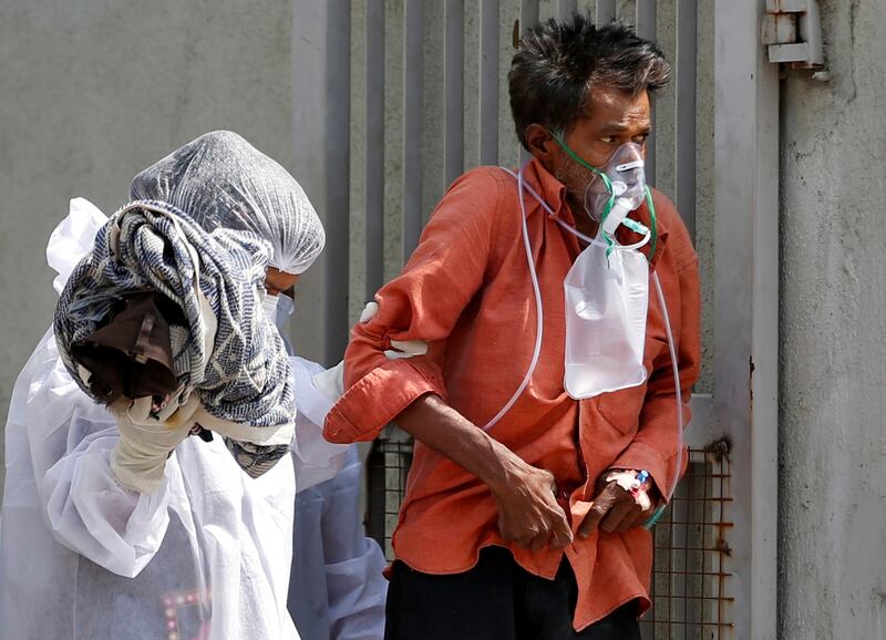 A patient with breathing problem is helped to walk towards an ambulance as he is being shifted to a hospital in Ahmedabad, India. Reuters