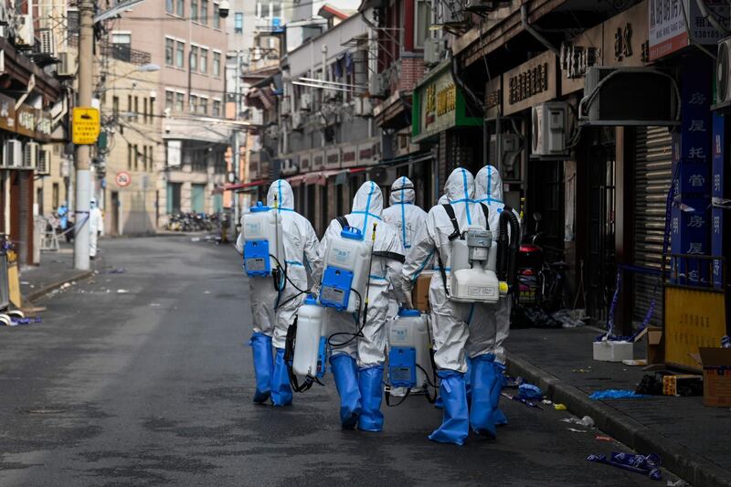Health workers in protective gear prepare to spray disinfectant in a blocked off area in Shanghai's Huangpu district, after residents were evacuated following the detection of a few cases of COVID-19 coronavirus in the neighbourhood. AFP