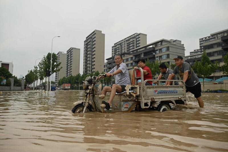 People wade through a flooded street following a heavy rain in Zhengzhou, in China's Henan province.