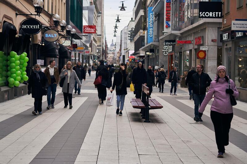 FILE - People walk along the main pedestrian shopping street in Stockholm, Sweden, Wednesday, March 25, 2020. The streets of Stockholm are quiet but not deserted. After a long, dark Scandinavian winter, the coronavirus pandemic is not keeping Swedes at home even while citizens in many parts of the world are sheltering in place and won't find shops or restaurants open on the few occasions they are permitted to venture out. (AP Photo/David Keyton, File)