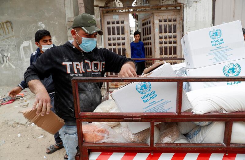 Palestinian workers distribute food supplies from the United Nations Relief and Works Agency (UNRWA) to a house in the Sheikh Redwan neighborhood of Gaza City, Tuesday, March 31, 2020. The United Nations has resumed food deliveries to thousands of impoverished families in the Gaza Strip after a three-week delay caused by fears of the coronavirus. (AP Photo/Adel Hana)
