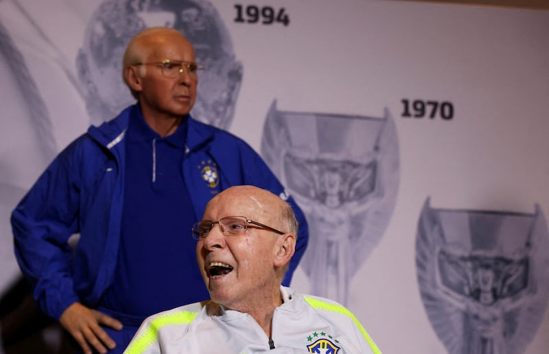 Brazilian former player and coach Mario Zagallo smiles next a statue representing him during a ceremony in his tribute in Rio de Janeiro, Brazil, October 20, 2022. Reuters