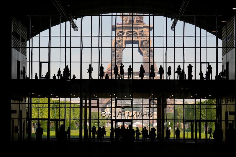 Visitors gather during a presentation visit of the "Grand Palais Ephemere", with the Eiffel Tower in the background, in Paris. AP Photo