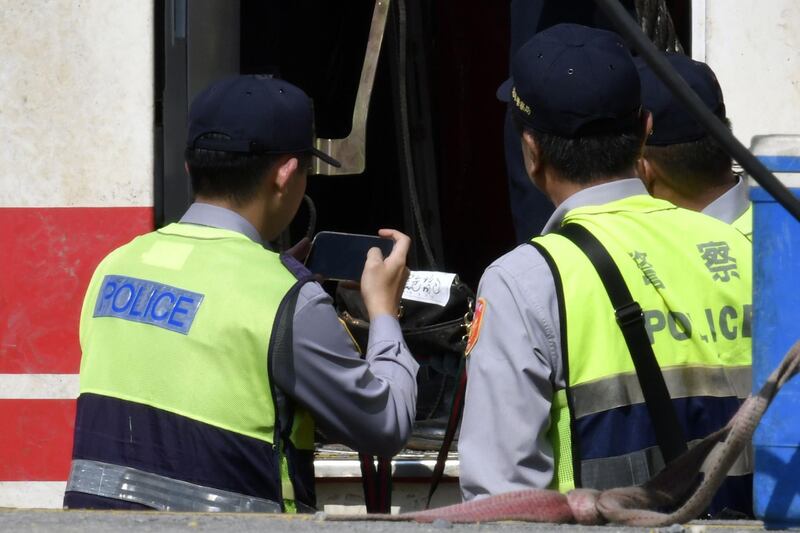 A policeman takes photographs of a passenger's belonging on the crashed Puyuma Express.  AFP