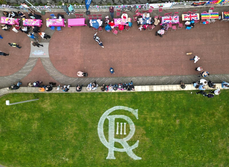 A cypher for King Charles is seen on the grass next to people celebrating the Big Lunch on the prom, in Morecambe. Reuters