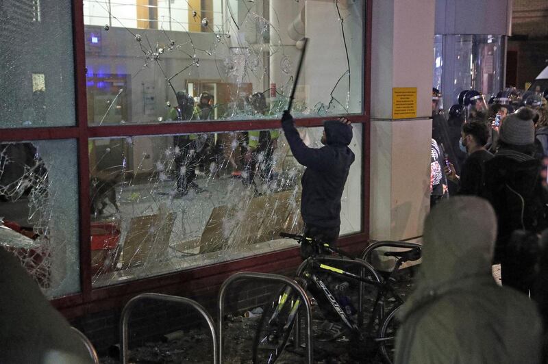 A protester hits a window with a stick at Bridewell Police Station, in Bristol. AP Photo