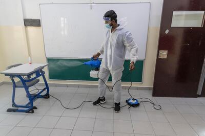 A cleaner at Gulf Model School sanitises the furniture. Antonie Robertson / The National 

