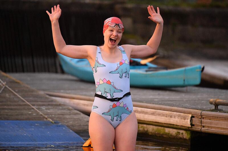 A swimmer reacts as she jumps into the water for a 'dawn dip' in the West Reservoir outdoor swimming lake in east London on December 2, 2020 as England emerges from a month-long lockdown to combat the novel coronavirus pandemic. England on December 2 exited a month-long lockdown into a new 3-tiered system of curbs with non-essential retail, leisure centres and salons all reopening but with some sectors, including hospitality, seeing tighter restrictions. / AFP / JUSTIN TALLIS
