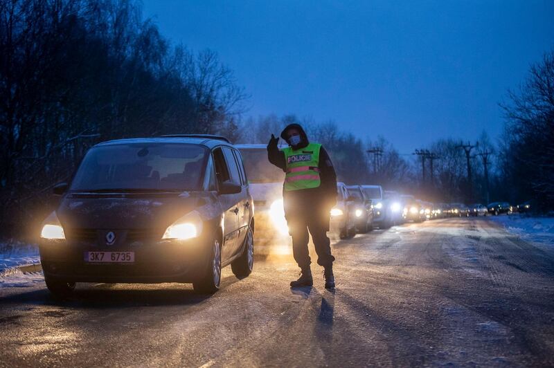 A police officer talks to a driver while people, many of them Czechs on their daily commute to their workplace in Germany, wait in line for a rapid Covid-19 test near the Czech-Germany border. Getty Images