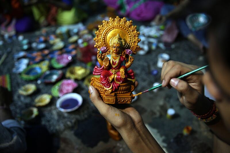 A child, studying under the guidance of Initiative for Viable Education (IVE) for underprivileged children, paints an idol of Goddess Laxmi as he prepares it ahead of Diwali festival in Amritsar, India. Raminder Pal Singh / EPA