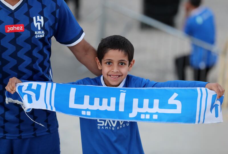 A young fan displays his scarf as he heads towards the stadium