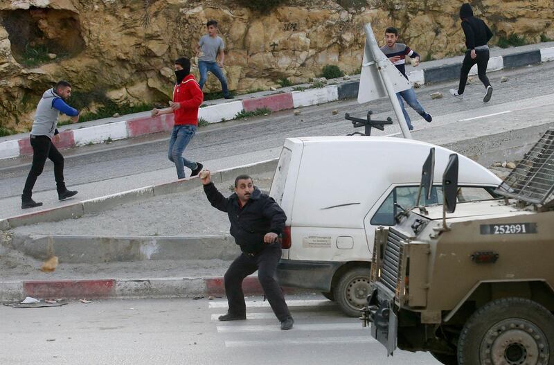 Palestinians throw stones at Israeli army vehicles after forces entered the village of Halhoul in the occupied West Bank on February 07, 2018.
A Palestinian stabbed a security guard at the entrance to an Israeli settlement and was shot dead in the latest violence in the occupied West Bank, Israel's military said. / AFP PHOTO / HAZEM BADER