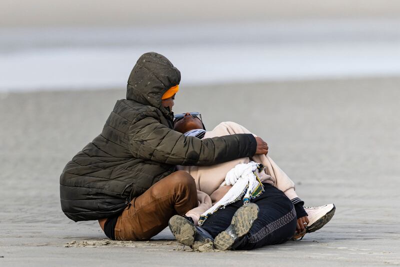 A migrant comforts another person who collapsed after failing to board a smuggler's boat. 