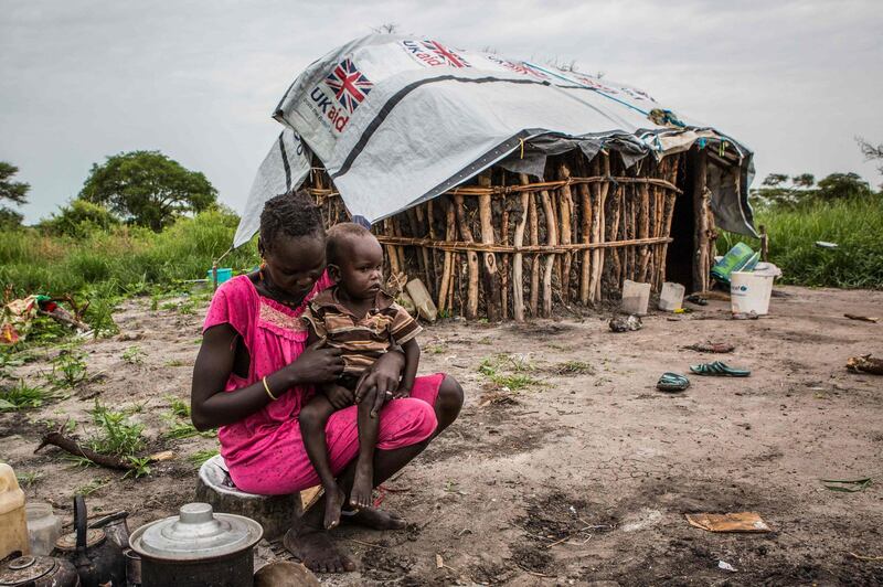 A picture taken on July 3, 2018, shows a woman cooking maize and sorghum dropped from air by a World Food Programme (WFP) plane in Jeich village in Ayod County, northern South Sudan. The small village in the bush surrounded by swamps and the ongoing conflicts is isolated by cutting off the road due to the floodwater during the rainy season. The air food dropping is the only option to deliver the aid for the residents mostly fled from conflict areas. / AFP / PATRICK MEINHARDT
