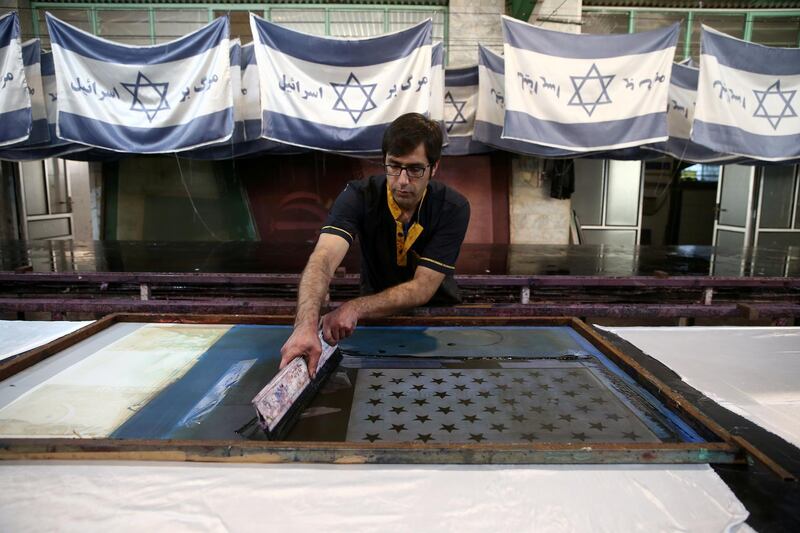 Iranian workers collect altered Israeli flags at a large factory that males US and Israeli flags for Iranian protesters to burn in Khomein City. West Asia News Agency via Reuters