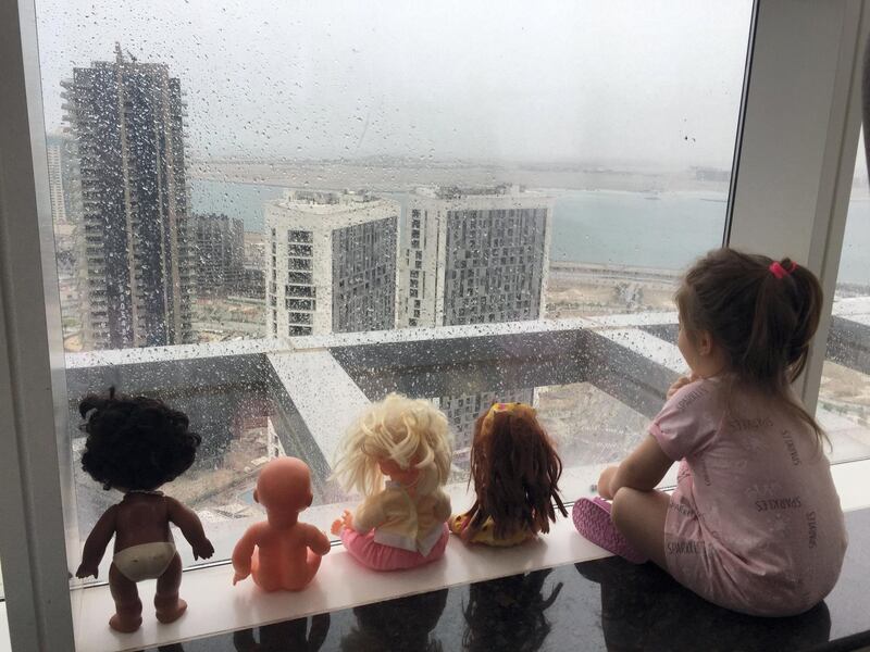 A child watches the UAE rains, accompanied by her toys. Courtesy of Hani Al Hussein