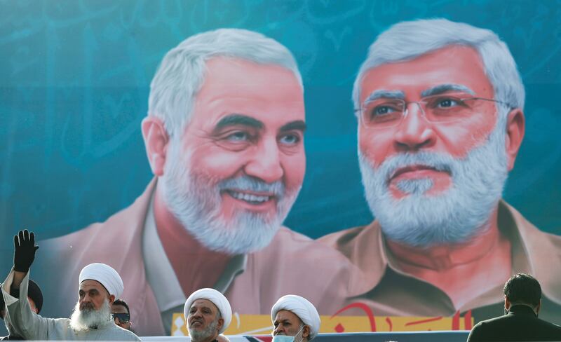 Iraqi clerics look on as they stand near a banner depicting senior Iranian military commander General Qassem Soleimani and Iraqi militia commander Abu Mahdi al-Muhandis, during a gathering marking the one year anniversary of their killing in a U.S. attack, in Baghdad, Iraq January 3, 2021. REUTERS/Thaier Al-Sudani