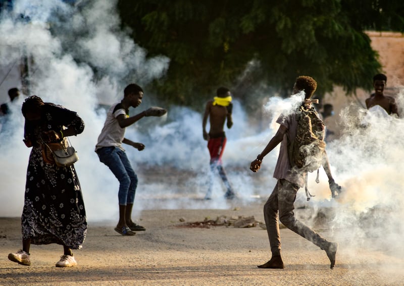 Sudanese youths confront security forces amid the tear gas.  AFP