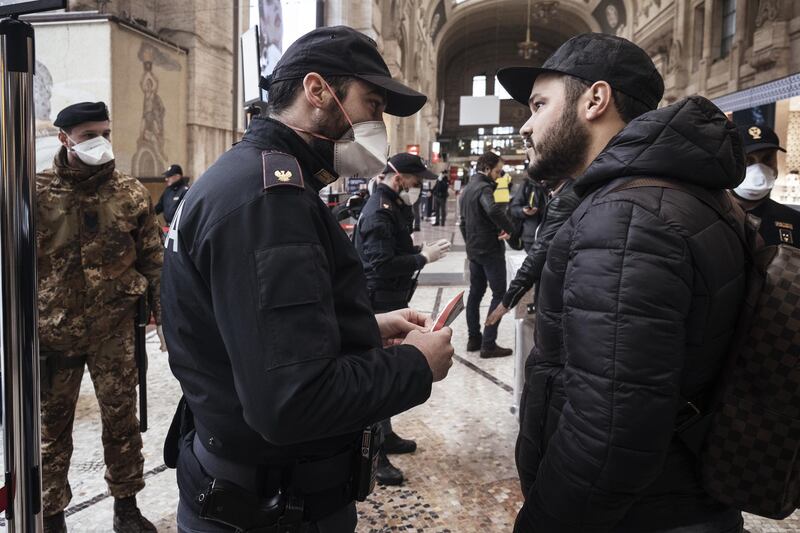 A police officer wearing a protective face mask speaks with a traveler at Centrale railway station in Milan, Italy. Bloomberg