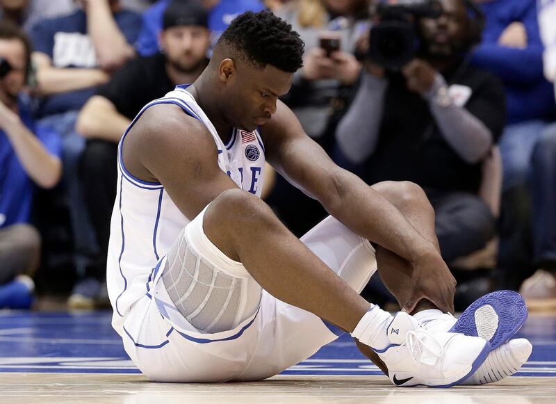 Duke's Zion Williamson sits on the floor following a injury during the first half of an NCAA college basketball game against North Carolina, in Durham, N.C., Wednesday, Feb. 20, 2019. Duke might have to figure out what the Zion Show will look like without its namesake. All because of a freak injury to arguably the most exciting player in college basketball. As his Nike shoe blew out, Williamson sprained his right knee on the first possession of what became top-ranked Duke's 88-72 loss to No. 8 North Carolina.(AP Photo/Gerry Broome)