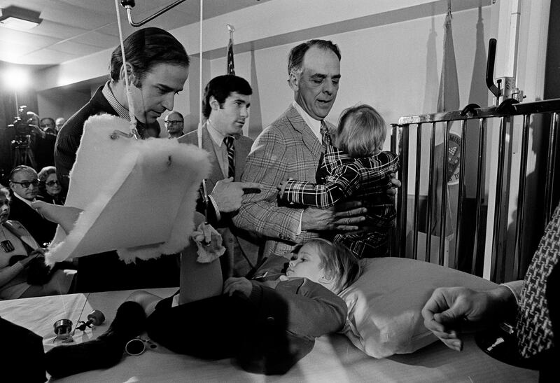 Joe Biden speaks with his bedridden son, Beau, before he was sworn in as the US senator from Delaware in January 1973. Mr Biden's first wife and daughter were killed in the car accident that injured his two sons. AP 