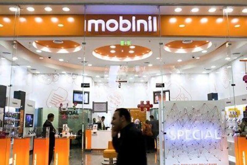 A pedestrian speaks on his mobile phone as he passes a Mobinil store, operated by Egyptian Co. for Mobile Services, in Cairo, Egypt, on Thursday, Feb. 16, 2012. France Telecom SA may spend about $2 billion to buy most of billionaire Naguib Sawiris's stake in their Egyptian wireless venture and delist the operator. Photographer: Shawn Baldwin/Bloomberg *** Local Caption *** 987144.jpg
