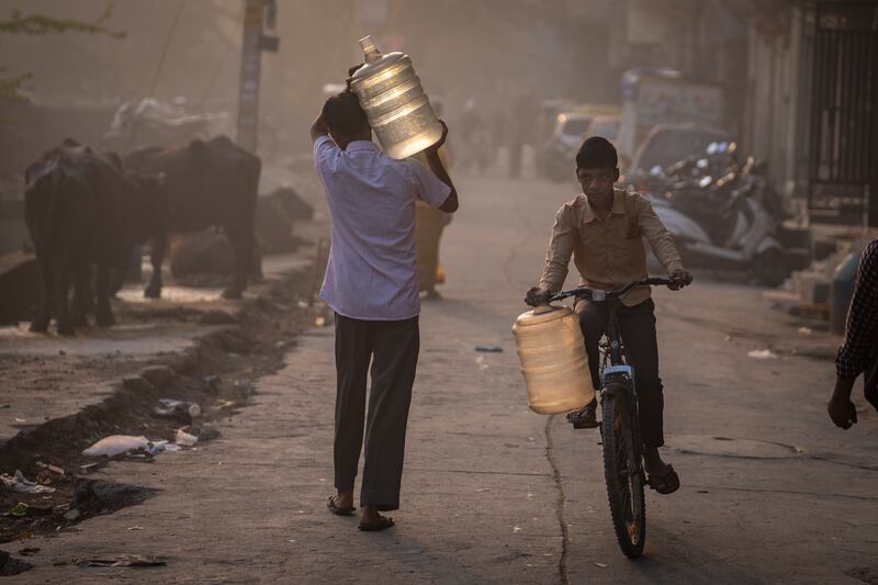 People carry water jugs in a residential area in New Delhi, India. AP