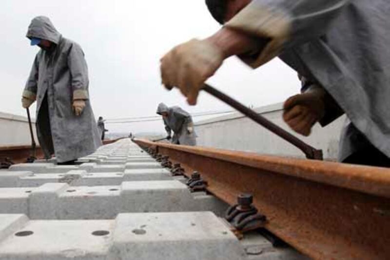 Workers lay railway tracks near a new railway station in Shanghai, China, on Monday, March 1, 2010. China is spending 5 trillion yuan ($732 billion) on new railways by 2020. Photographer: Qilai Shen/Bloomberg