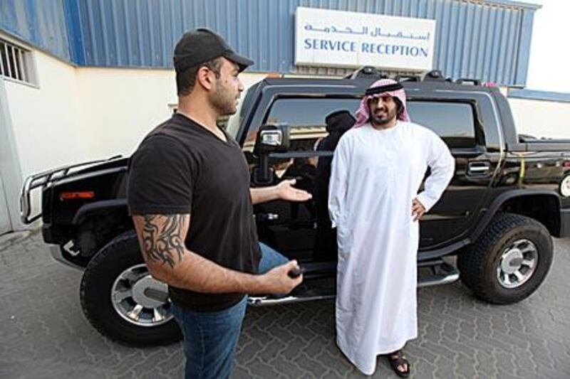 Firas al Rumaithy, left, and his brother Khalifa take their Hummer to be serviced in Musaffah yesterday. According to the former, the car is '"a bit of a disappointment".