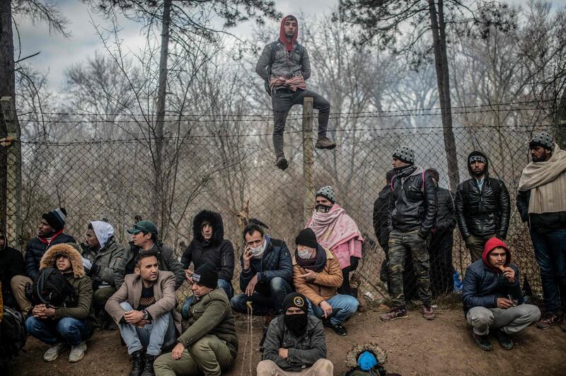 Migrants sit waiting near the buffer zone at Turkey-Greece border, at Pazarkule, in Edirne district.  AFP