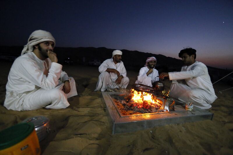 Emiratis gather around an open fire at the Liwa desert. The UAE was named the most desirable country to live in for the 10th consecutive year by young Arabs polled for the 2021 Arab Youth Survey. Photo: Karim Sahib / AFP
