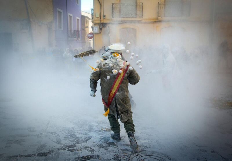 Revellers dressed in mock military garb throw eggs as they take part in the "Els Enfarinats" battle in the southeastern Spanish town of Ibi.  AFP