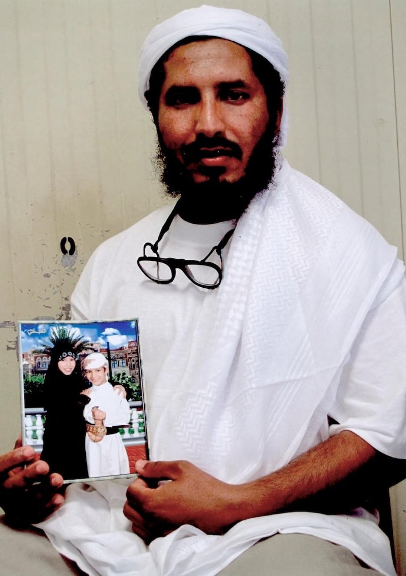 FILE - This undated file photo provided by Ramzi Kassem, an attorney for Mohammed Ahmed Haza al-Darbi, shows al-Darbi from Saudi Arabia holding a photograph of his children, as he sits for a portrait inside the detention center at the U.S. base at Guantanamo Bay, Cuba. The Pentagon said Wednesday, May 2, 2018,  that Al-Darbi, who was sentenced to 13 years in October 2017 by a military commission, has been sent to his native Saudi Arabia to serve out the remainder of his sentence. (Ramzi Kassem via AP, File)