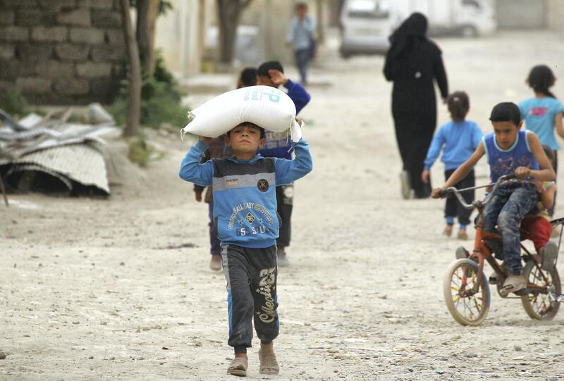 A boy carries food aid given by UN's World Food Programme in Raqqa, Syria April 26, 2018. REUTERS/Aboud Hamam