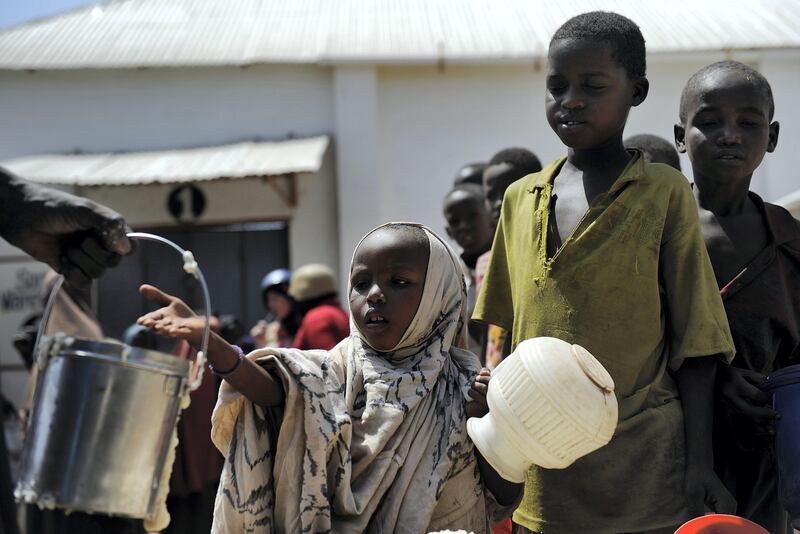 Displaced Somali children queue as they wait for food-aid rations on January 19, 2012 at a distribution centre during a visit to assess the progress of relief efforts by UN Office for the Coordination of Humanitarian Affairs (OCHA) in the capital Mogadishu. Regular explosions from the Al-Qaeda linked Shebab's guerrilla attacks -- including suicide bombers and homemade explosives -- still rock the city, where some 180,000 people have fled hunger in the hope of finding aid.     AFP PHOTO/ TONY KARUMBA                     ***TO GO WITH AFP STORY BY AUDE GENET**** / AFP PHOTO / TONY KARUMBA