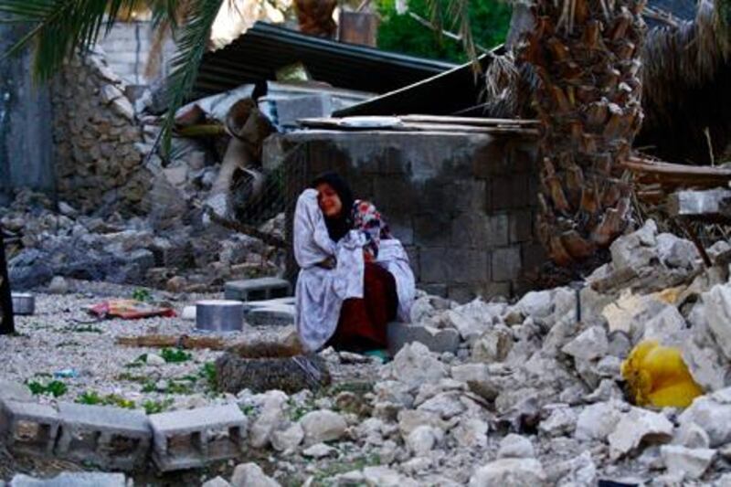 An Iranian woman sits among the rubble of buildings after an earthquake struck southern Iran, in Shonbeh, Iran,.