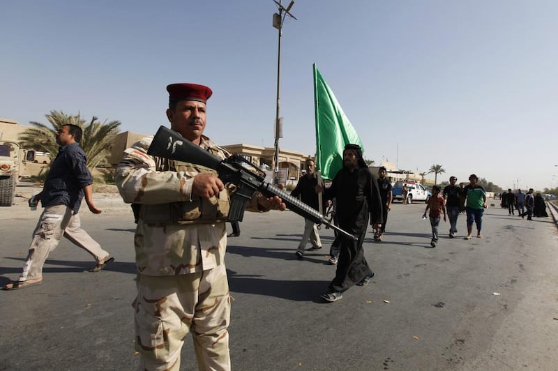 An Iraqi soldier stands guard as Shiite pilgrims walk to the holy city of Kadhimiya during a religious ritual commemorating the anniversary of Imam Mohammed Al Jawad's death. Saad Shalash / Reuters 